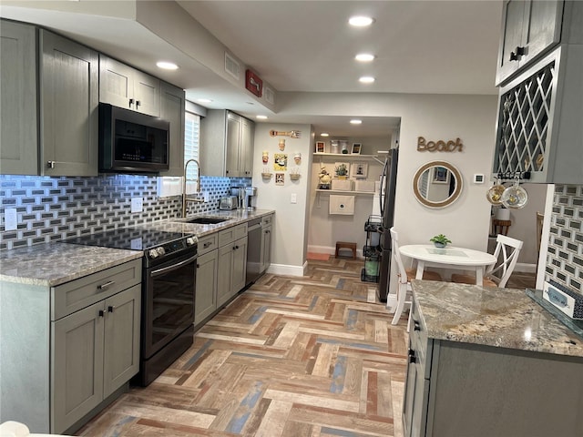 kitchen with black electric range, stone counters, stainless steel dishwasher, sink, and gray cabinetry