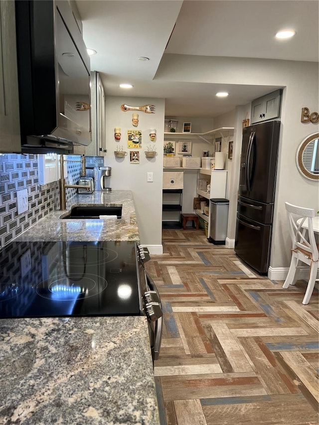 kitchen with light stone countertops, backsplash, dark parquet floors, black fridge with ice dispenser, and electric range