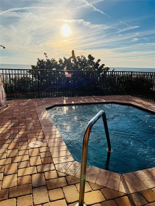 pool at dusk featuring a water view