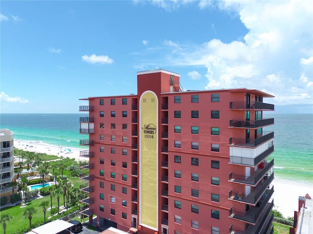 view of building exterior featuring a water view and a beach view