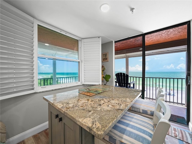 kitchen with a water view, hardwood / wood-style floors, and light stone countertops