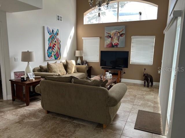 tiled living room with a towering ceiling and a notable chandelier