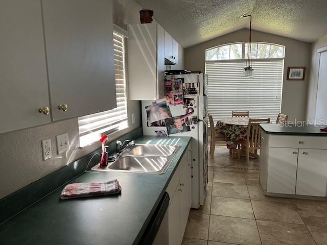 kitchen featuring vaulted ceiling, white cabinets, a textured ceiling, and a sink