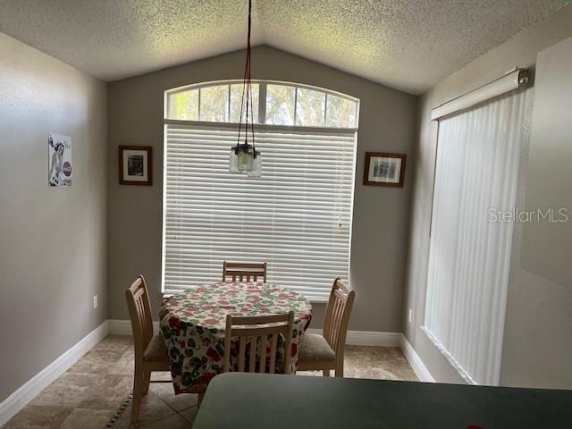 tiled dining area featuring a textured ceiling and vaulted ceiling