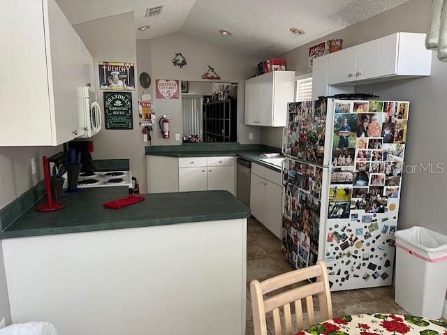 kitchen featuring tile patterned flooring, vaulted ceiling, appliances with stainless steel finishes, and white cabinets