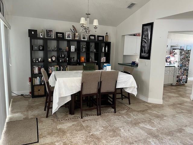 tiled dining area featuring lofted ceiling and a chandelier