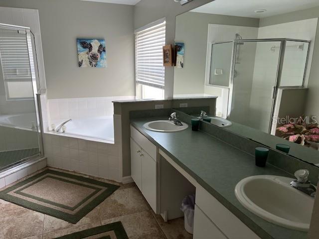 bathroom featuring double vanity, plus walk in shower, and tile patterned floors