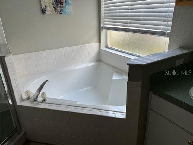 bathroom featuring vanity and tiled bath