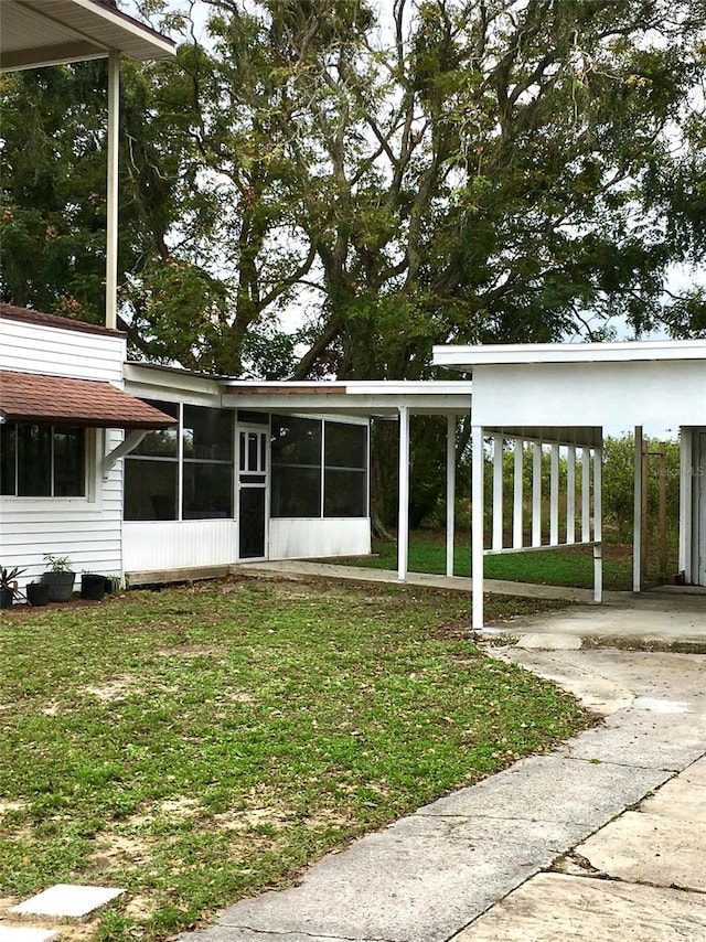 view of front facade with a sunroom, a front lawn, and a carport