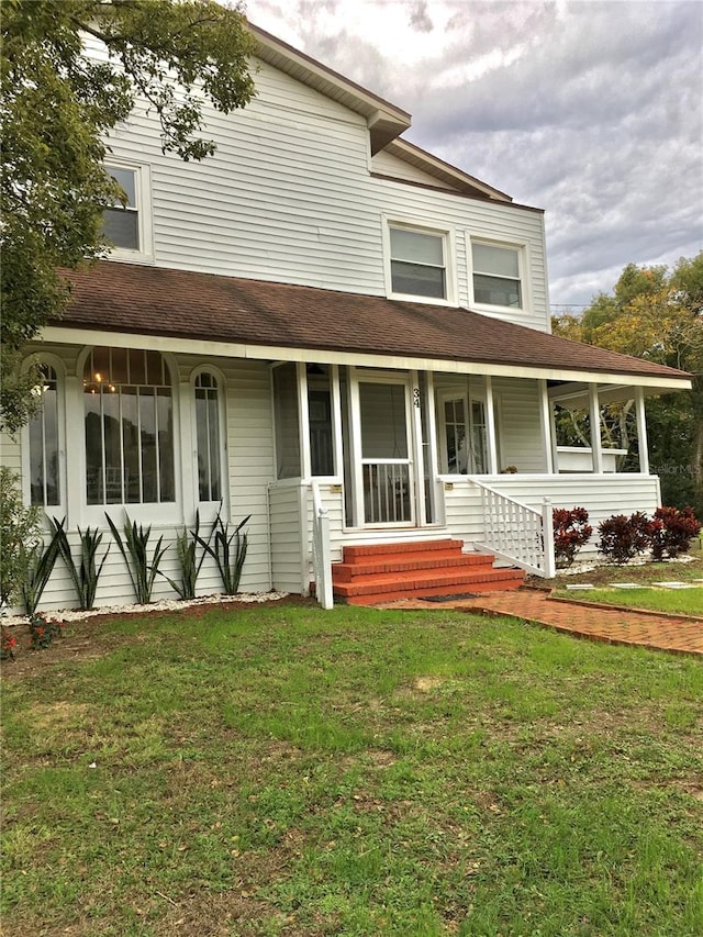 farmhouse-style home featuring a porch and a front yard