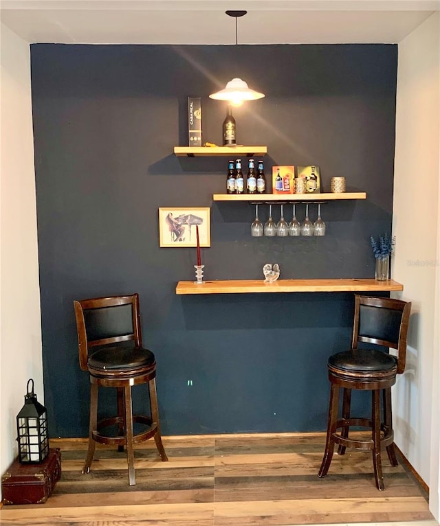 bar featuring wood-type flooring and decorative light fixtures