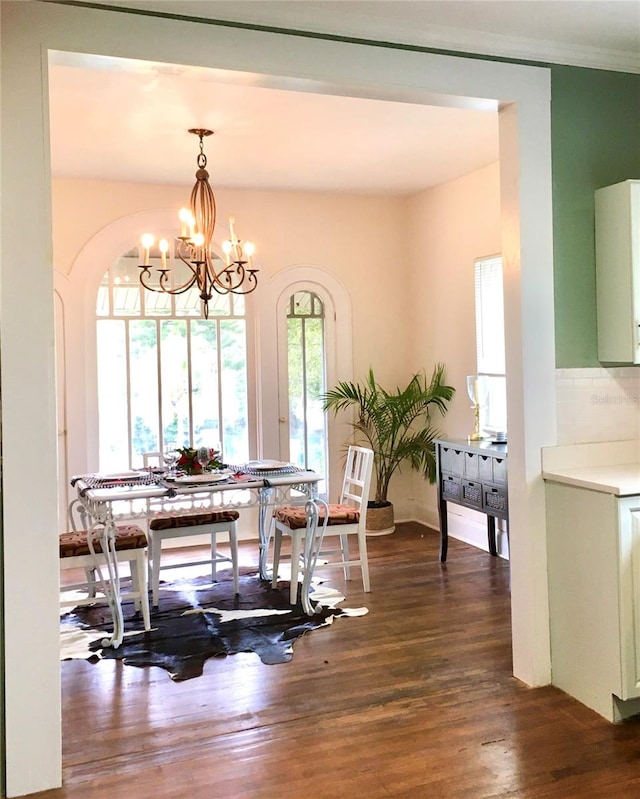 dining space featuring dark wood-type flooring and an inviting chandelier