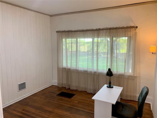 office area with dark hardwood / wood-style floors, wood walls, crown molding, and a healthy amount of sunlight