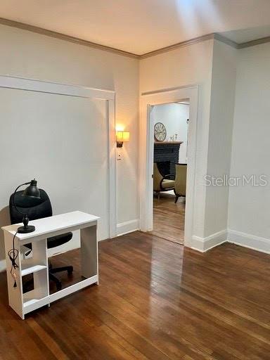 corridor featuring dark wood-type flooring and ornamental molding