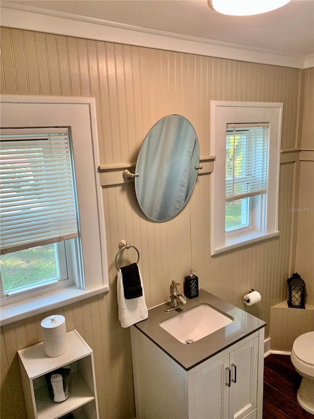 bathroom featuring hardwood / wood-style flooring, crown molding, vanity, and toilet