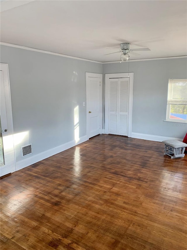 empty room featuring dark wood-type flooring, crown molding, and ceiling fan