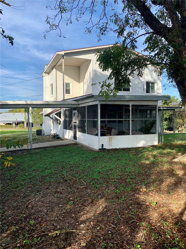 back of property featuring a lawn, a sunroom, and central AC