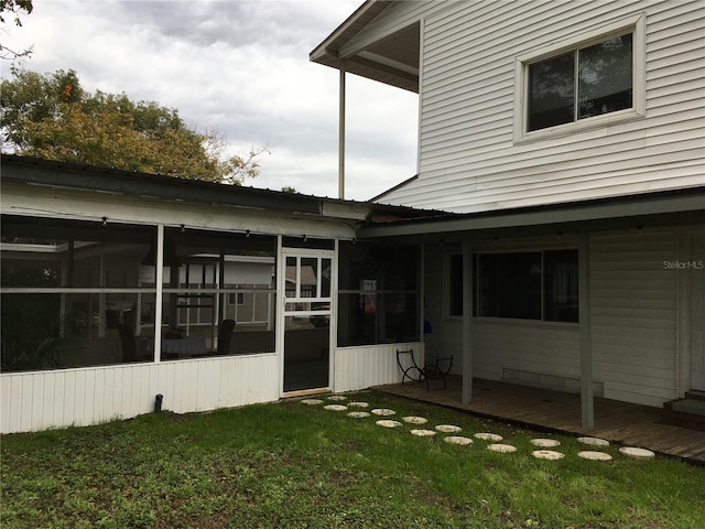 rear view of property with a sunroom and a lawn