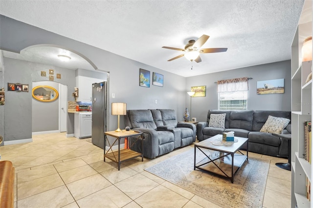 tiled living room with ceiling fan and a textured ceiling