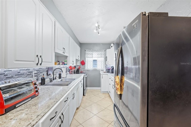 kitchen featuring light stone countertops, stainless steel appliances, tasteful backsplash, white cabinets, and light tile floors