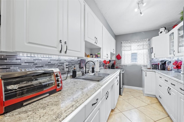 kitchen with white cabinets, sink, backsplash, and light tile floors