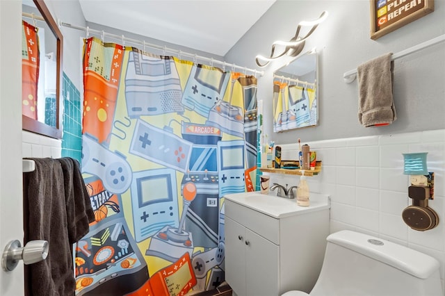 bathroom with toilet, tile walls, and large vanity