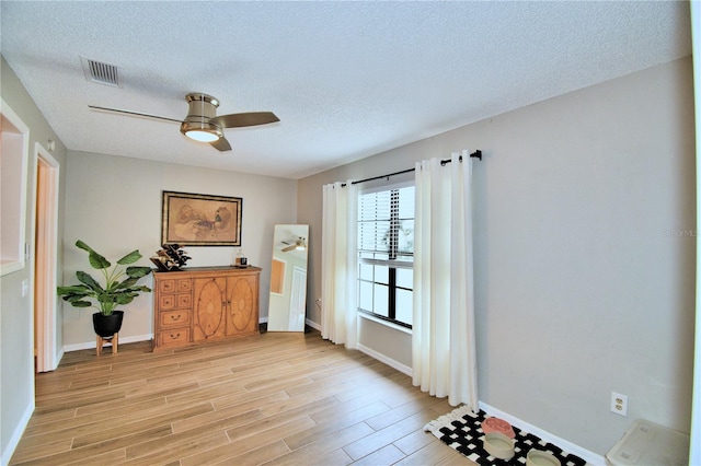 interior space featuring a textured ceiling, light hardwood / wood-style floors, and ceiling fan