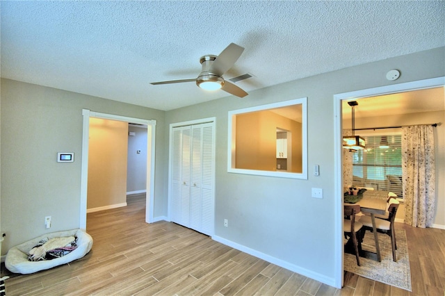 unfurnished room featuring a textured ceiling, light hardwood / wood-style floors, and ceiling fan