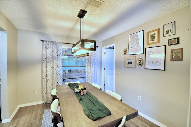dining space featuring a textured ceiling and light hardwood / wood-style floors