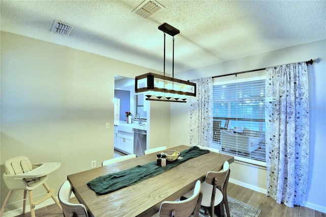 dining area featuring a textured ceiling, wood-type flooring, and sink