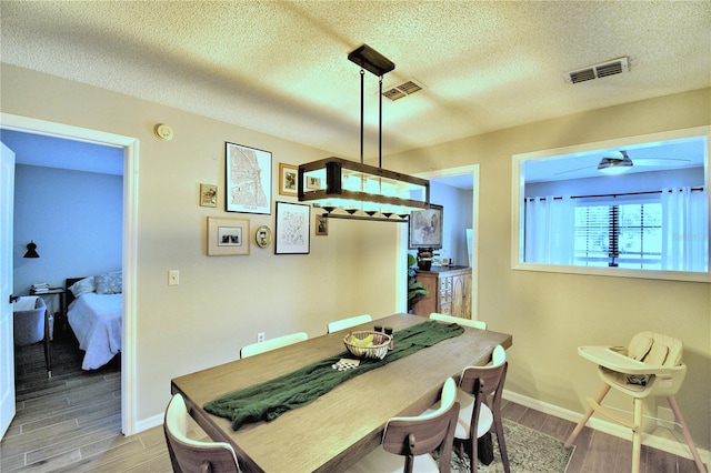 dining room featuring a textured ceiling, ceiling fan, and light wood-type flooring