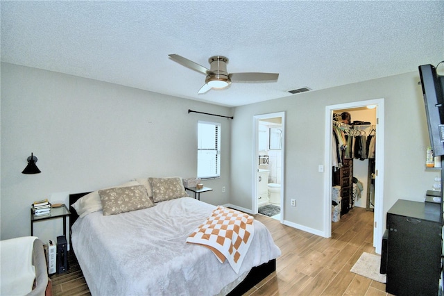 bedroom with ceiling fan, a walk in closet, ensuite bathroom, light hardwood / wood-style flooring, and a closet
