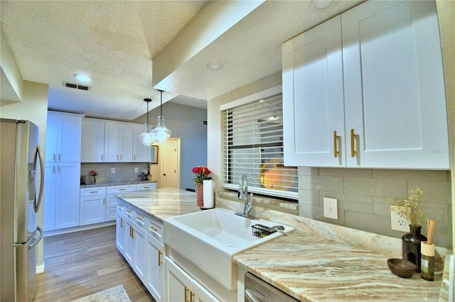 kitchen featuring backsplash, light stone countertops, stainless steel fridge with ice dispenser, and white cabinetry