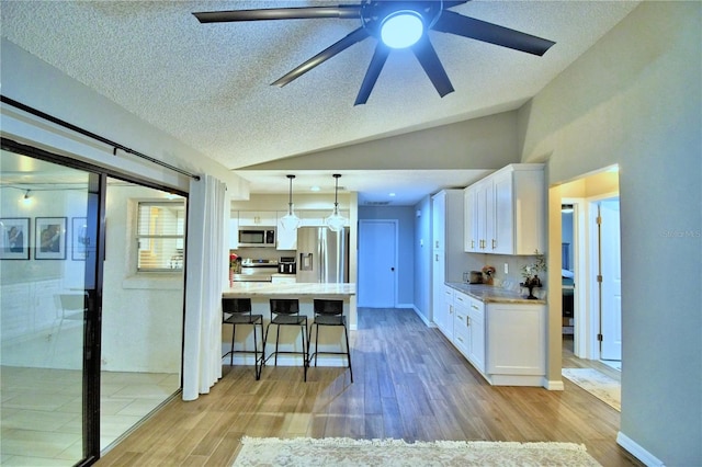 kitchen featuring decorative light fixtures, white cabinetry, ceiling fan, light hardwood / wood-style floors, and stainless steel appliances