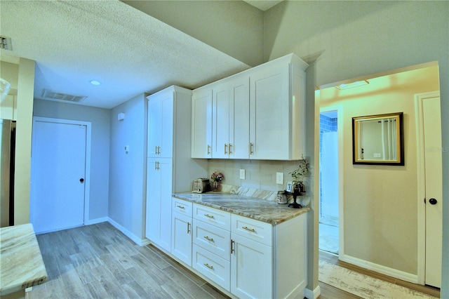 kitchen featuring white cabinetry, tasteful backsplash, and light wood-type flooring