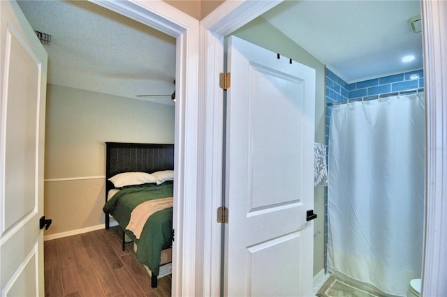 bedroom featuring a textured ceiling, ceiling fan, and dark hardwood / wood-style flooring