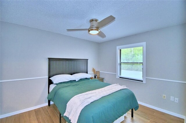 bedroom featuring a textured ceiling, light hardwood / wood-style floors, and ceiling fan