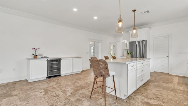 2300 N Scenic Hwy Unit 111, Lake Wales, FL 33898 - kitchen with beverage cooler, freestanding refrigerator, crown molding, white cabinetry, and a kitchen bar