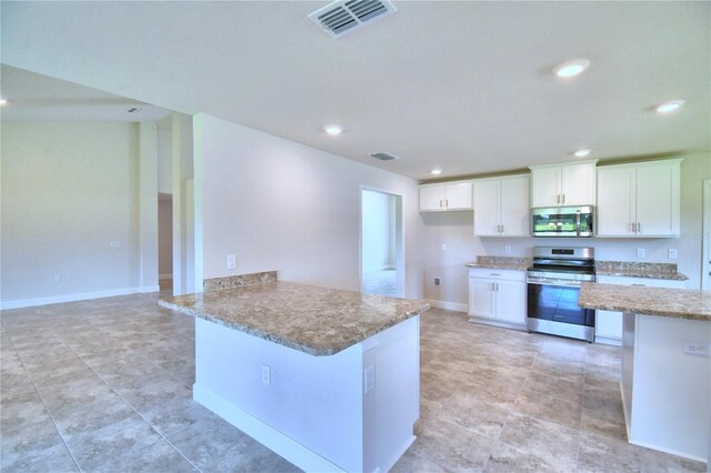 kitchen with white cabinets, stainless steel appliances, light stone counters, and kitchen peninsula