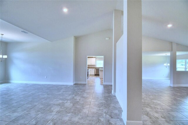 tiled spare room featuring lofted ceiling and an inviting chandelier