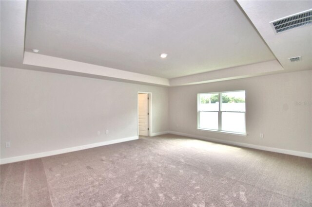 carpeted empty room with a tray ceiling