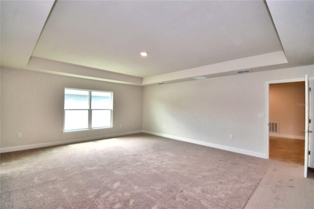 carpeted empty room featuring a raised ceiling