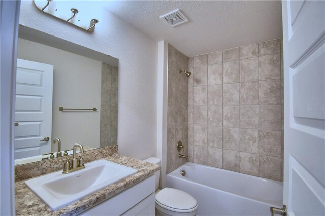 full bathroom with toilet, a textured ceiling, tiled shower / bath, and vanity