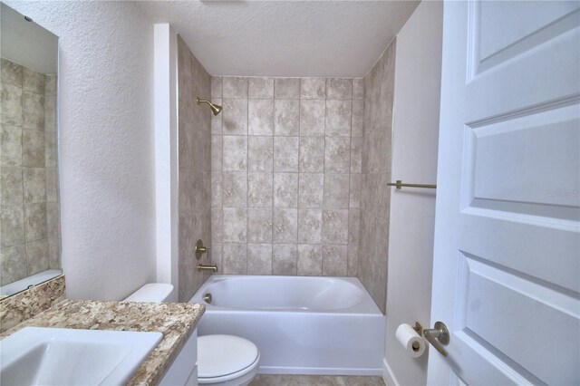 full bathroom featuring vanity, toilet, tiled shower / bath, and a textured ceiling