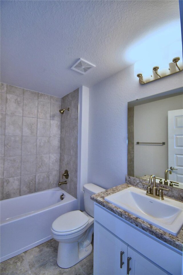 full bathroom featuring a textured ceiling, tiled shower / bath combo, vanity, and toilet