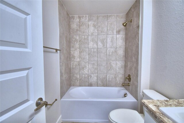 full bathroom featuring toilet, tiled shower / bath, and vanity