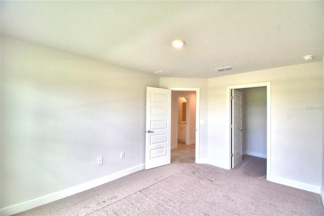 unfurnished bedroom with carpet floors, a closet, and a walk in closet