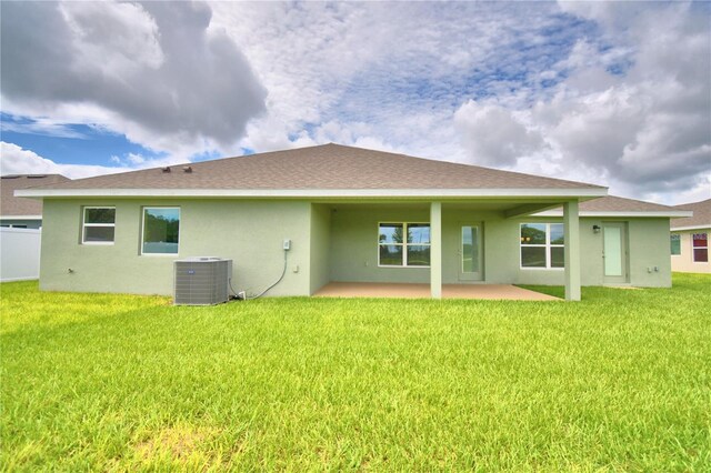 rear view of house with central AC, a yard, and a patio