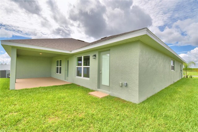 back of property with a patio area, a yard, and central AC