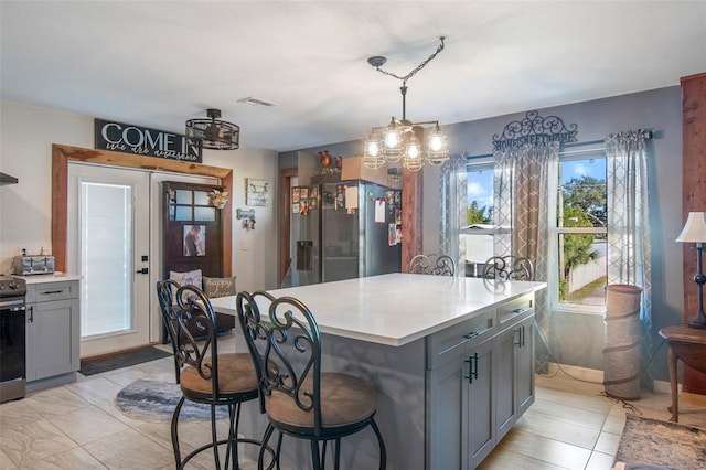 kitchen featuring decorative light fixtures, a kitchen island, a notable chandelier, gray cabinets, and appliances with stainless steel finishes